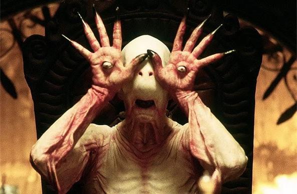 Pans Labyrinth demon where the demons head has no eyes  but the eyes are in the palms of his hands.

He's holding his hands, palms open where his eyes would be.

The demon is pale white and pink. No hair. No teeth. Chopped off nose but nostrils.
