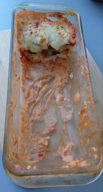 Un molde de cristal rectangular en el que solo quedan las sobras de un pastel de verduras gratinado.