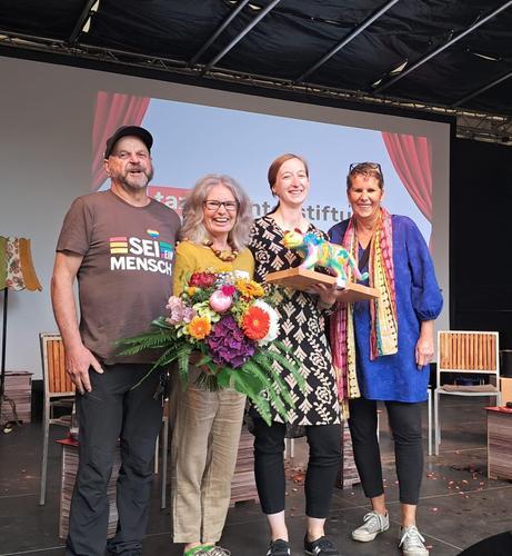 Vier Mitglieder des Bündnis Kaiserslautern gegen Rechts mit Trophäe und Blumen af der Bühne der Preisverleihung in Halle (Saale).