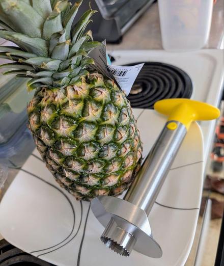 Whole pineapple on a plate  with slicer beside it