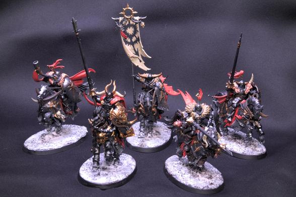 Five miniatures from the game Age of Sigmar, representing Chaos Knights. Each miniature is a knight riding a horse with heavy armor in dark metal color. All knights wear a red cape, a heavy shield and a lance, except two that carry a music horn and a large flag. The armor is decorated with gold trim. The red from the capes dominates as the main highlight color, with some details in bone white, khaki and skin color. The large flag has a chaos symbol painted on it.