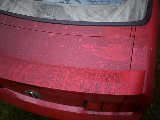 The back of my car, still dirty. The spoiler has remnants of a friendly hand drawn message. The rain on the highway left the back of the car very dirty.