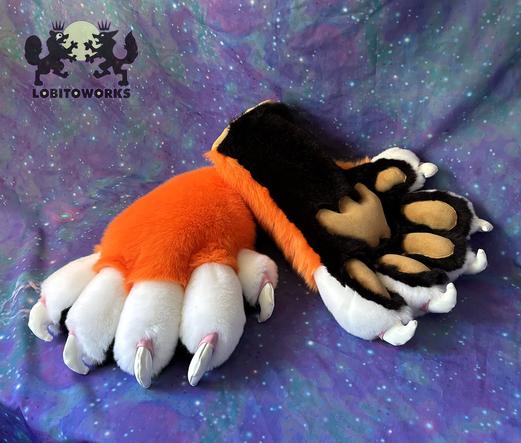 Orange, white, and black fursuit hands with big padded fingers and large white claws with pink cuticles. The pawpads are tan in color and stuffed so they stick out, and the palms are black. The hands are displayed in front of a blue-violet space themed backdrop.