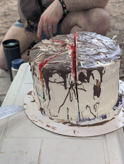 Photo of a cake all in white with chocolate drizzled over the top and sides.