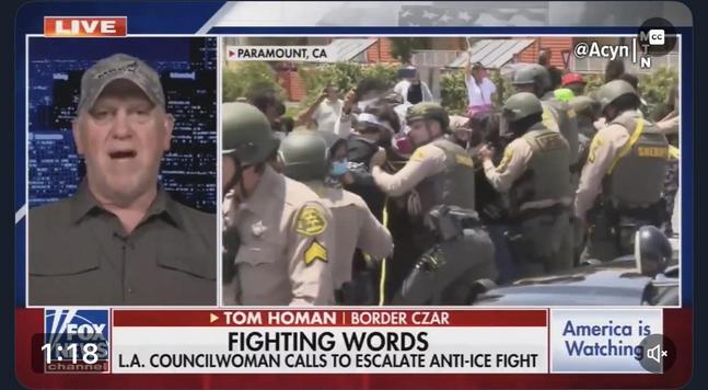 A split-screen news segment features Tom Homan, identified as the "Border Czar," discussing issues related to immigration enforcement. The background shows a protest scene in Paramount, CA, with law enforcement officers engaged with a crowd of demonstrators. Text LA Councilwoman call for anti ICE fight: