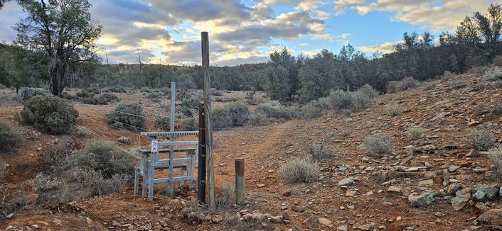 Stile leading into ochre coloured Gully lined with saltbush