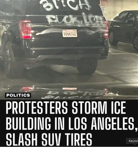 Image of a parked I.C.E. SUV in a garage with the back window spray painted "Bitch fuck ICE" and the rear tires slashed. The caption reads "Protestors storm ICE building in Los Angeles, slash SUV tires."