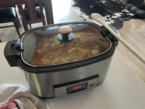 A slow cooker in which the fixings for a rich chicken and vegetable soup are visible.