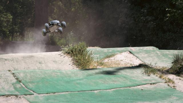 an RC stadium truck jumping, leaving a trail of dust in the air