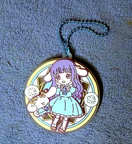A circular rubber tag of Tomoyo from Cardcaptor Sakura with Cinnamoroll ears with Cinnamoroll by her side