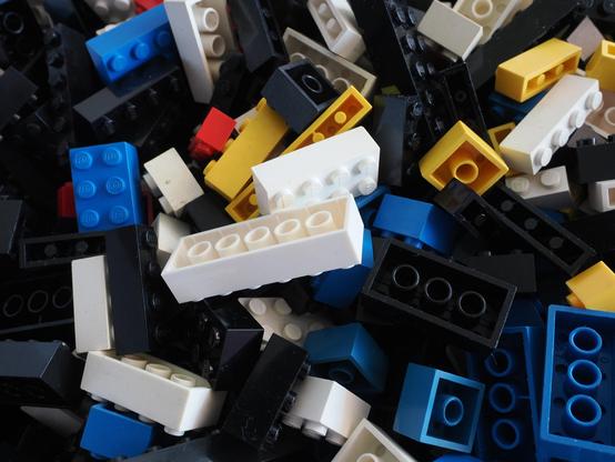 Nahaufnahme eines Haufens Legosteine in den Farben Schwarz, Weiß, Blau, Gelb und einige wenige in Rot.