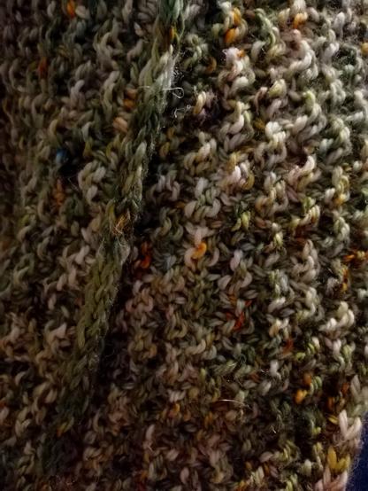 close up of a textured hand knit cowl in mossy green tones