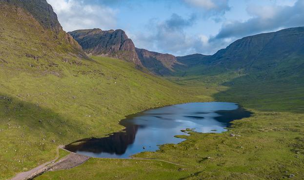 A blue loch surrounded by steep green cliffs.