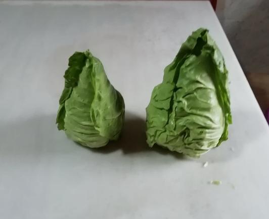 Foto de una mesa de mármol donde hay dos repollos recién cosechados. Son de la variedad "Corazón de buey". Tienen las hojas verdes y la forma de una gota de agua. Supongo que el nombre será por su parecido con un corazón de buey, aunque no he visto nunca ninguno.