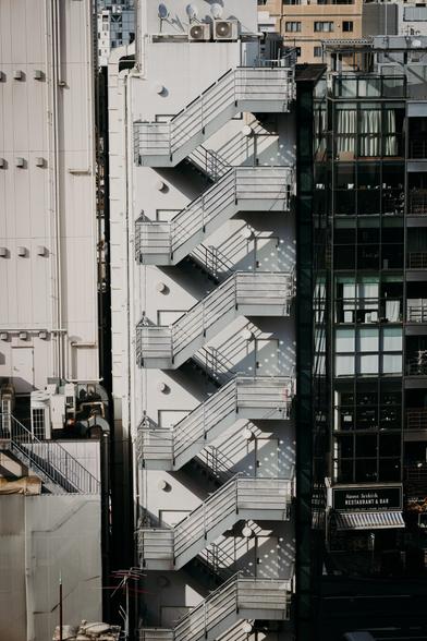 photo of the emergency staircase outside of a building, with the sun casting nice geometrical shadows of the stairs onto the building wall