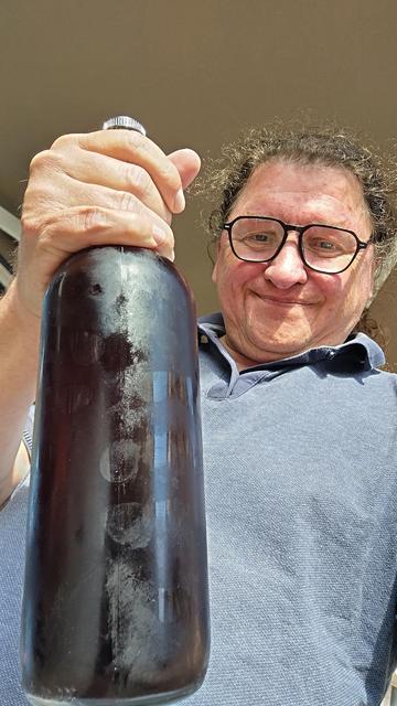 Ich halte mit zufriedenem Gesichtsausdruck eine beschlagene Flasche Sangria in die Kamera.