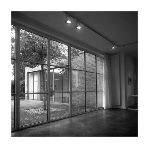 Large glass door with a view of an inner courtyard with a tree and brick walls, modern interior with parquet flooring