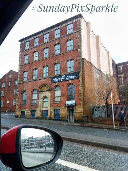 A boring old brown building with a tiny dilapidated door bottom right, above which is a sign declaring House Of Glitter