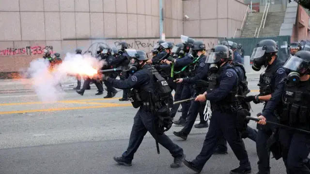 A police officer uses stun grenades as officers approach protesters gathered around the Los Angeles Federal Building after multiple detentions by ICE agents in downtown Los Angeles on Friday January 6, 2025.   (Reuters/Daniel Cole).