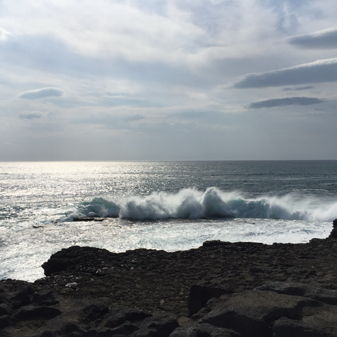 im vordergrund steinküste … oben wolkiger himmel … im zentrum das meer auf dem sich wellen türmen … trotz farbfoto gibt es fast nur schwarz-, grau- und weißtöne