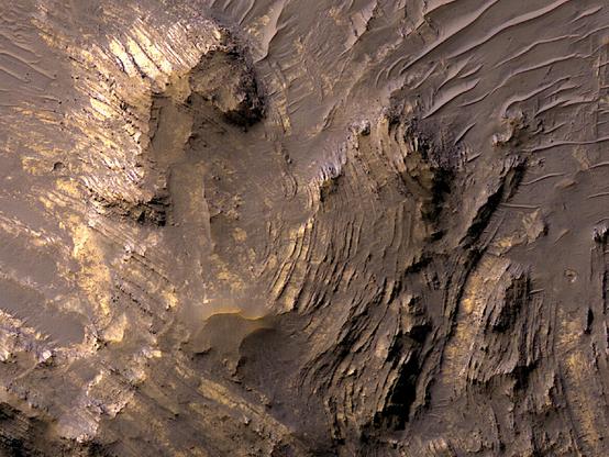 La strada verso la cima comporta sfide lungo il percorso e più si sale, più le conoscenze acquisite durante il viaggio diventano abbondanti e inestimabili. È questo il caso dei complessi crateri da impatto, le cui strutture centrali si fanno strada a fatica dalle profondità del sottosuolo per salire sempre più in alto. Quando fanno capolino dalla superficie, ci offrono un'istantanea delle intense sollecitazioni e temperature a cui sono stati sottoposti, nel loro percorso per vedere il cielo.

Tuttavia, non tutte le strutture centrali dei crateri hanno una forza sufficiente per mantenere il picco, per cui, una volta persa tutta l'energia, collassano verso l'interno, formando una fossa o una depressione centrale. È il caso del sollevamento del cratere Betio, del diametro di 32 chilometri, situato a sud delle Valles Marineris. Questo ritaglio composito a colori HiRISE mostra una parte della depressione centrale di Betio.