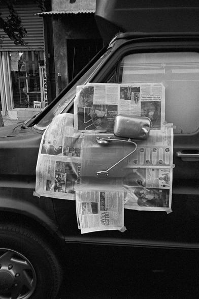 picture of a van with newpapers taped around the side mirror, unclear why