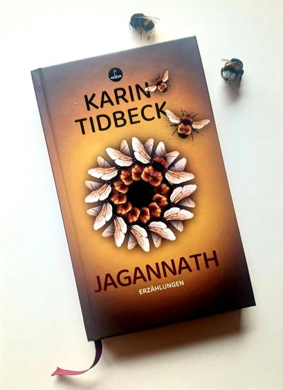 Foto des Buches, auf dessen Cover mittig ein Kreis aus Hummelflügeln und -leibern abgebildet ist, aus dem sich zwei der Tiere bereits gelöst haben, die von dem von einer Art Corona umgebenen Kreis über das in Brauntönen gehaltene Cover davonfliegen. Oberhalb des Buches – in Flugrichtung liegen zwei weitere Hummeln auf dem hellen Hintergrund, vor dem das Buch fotografiert ist.