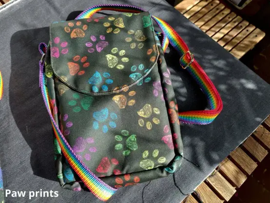 A black version of the same bag with colorful paw prints on the fabric.