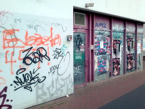 Foto einer schmutzigen, mit Graffiti verschmierten Wand und Tür in der Ruine des Ihmezentrums in Hannover-Linden.