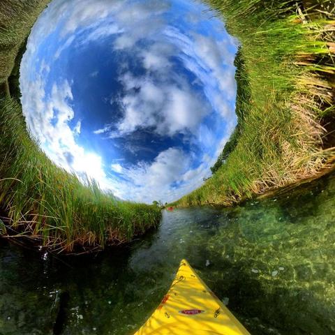 One of a series of photographs in which two people are pictured hiking, biking, and kayaking throughout a beautiful and verdant state park in central Minnesota under cloudy blue late-summer skies.