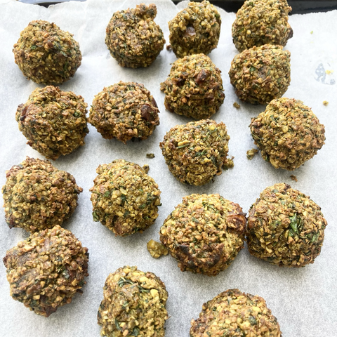 17 balls of cooked falafel in rows of four until the bottom where they are a bit random. They are all shapes and sizes. They sit on parchment paper