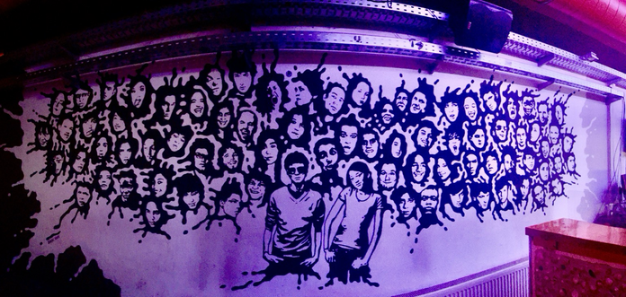 Graffiti auf der Wand neben der Bar mit ca. 70 schwarz-weiß aufgemalten Köpfen