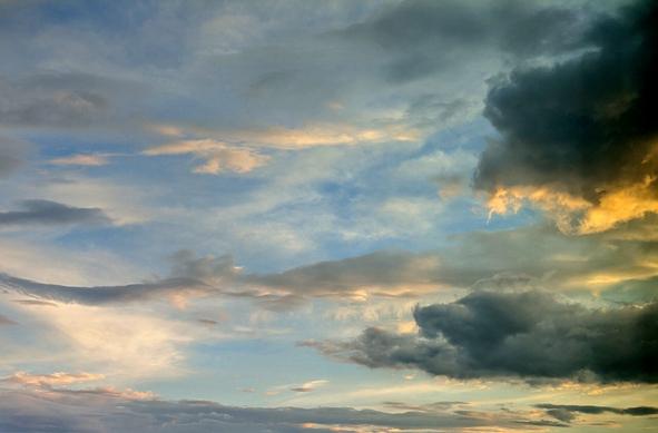 The sky at sunset with shadowy clouds highlighted in orange