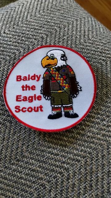 A round patch that says "Baldy the Eagle Scout" with Baldy standing to the right of the text.