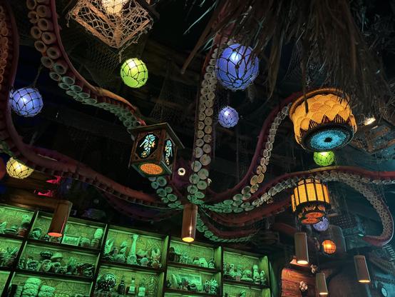 The ceiling of the bar with tentacles of Kiki the Kraken reaching out around the bar. There are numerous glass floats and tiki lamps suspended from.the ceiling.