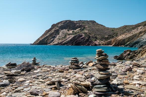 Stacks of rocks by a turquoise sea with a rocky hill in the background, Palaikastro, Crete.