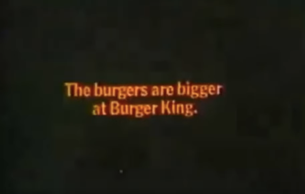 A screenshot from a 1968 Burger King advert that says "the burgers are bigger at Burger King" in orange text on a black background.