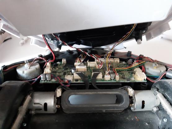 Couvercle de l'aspirateur ouvert avec plein de câbles qui relient des composants électroniques