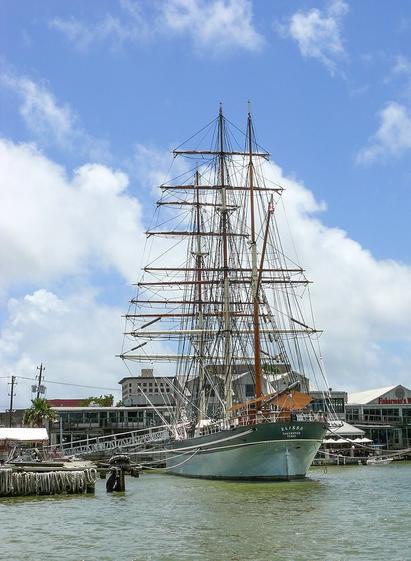 The tall ship Elissa a three masted sailing ship sits pier side.