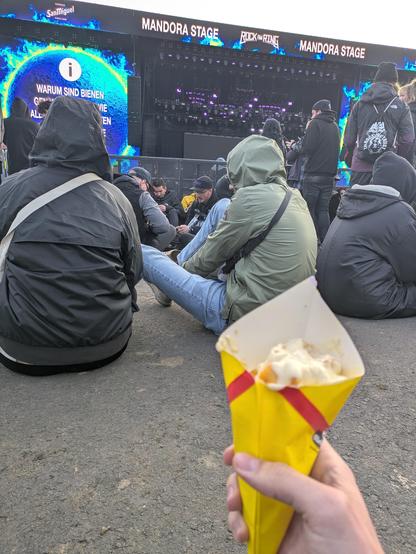 Ich sitze mit meine Tüte Pommes vor einer großen Bühne nie Rock am Ring