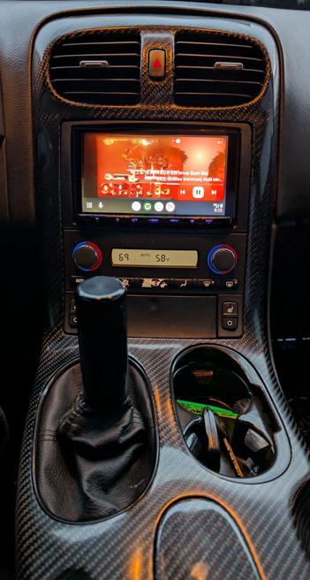 The center dash console of a C6 Corvette shows a high gloss clear finish over 2x2 weave carbon fiber after having been subjected to a lengthy manual refinishing process.