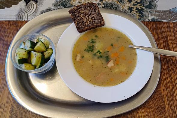 Die Suppe mit Gurkensalat und Vollkornbrot serviert