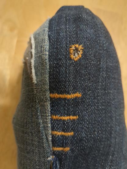 Close-up of the face from the side. Better view of the embroidery, and you can now see that the eyes are a little piece of black denim with a white dot embroidered in them.