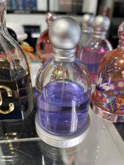 a photograph of a perfume bottle with a violet colored perfume