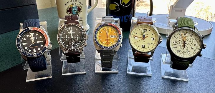 five wristwatches arranged on a desk