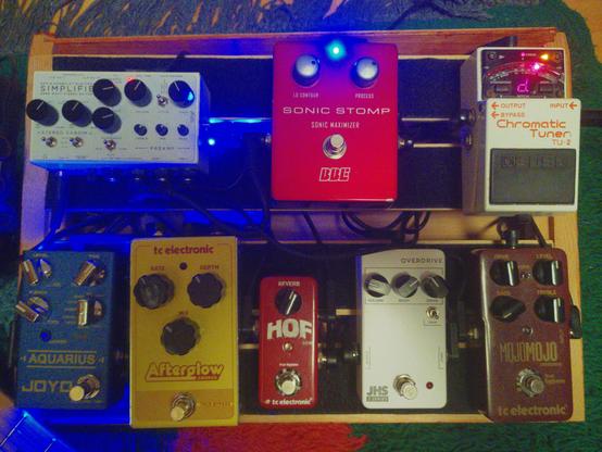 Pedalboard with eight pedals: Boss Tuner, Sonic Stomp, Simplifier Preamp, Aquarius Delay, Afterglow Chorus, Mini HOF Reverb, Series 3 Overdrive, Mojomojo Overdrive.