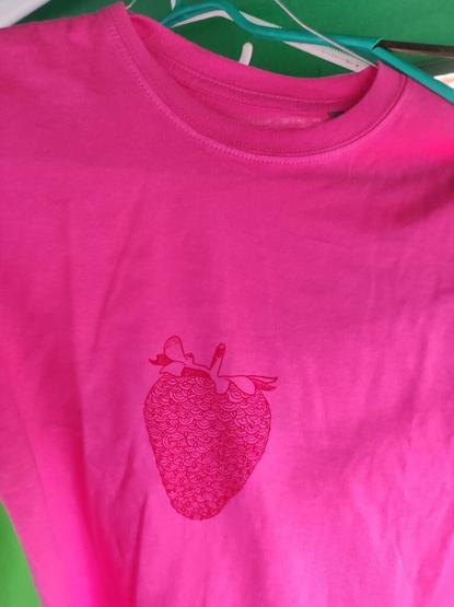 A photo of another pink shirt with a red strawberry print on it.