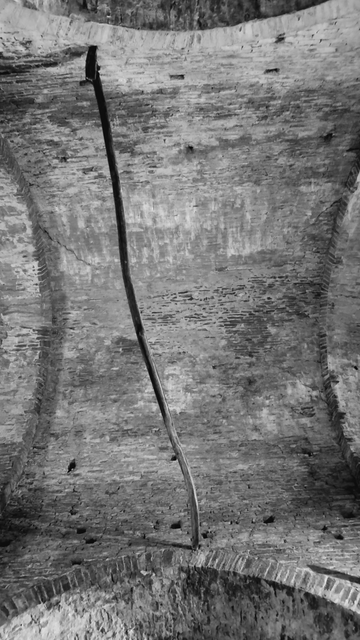 A crooked tree log crosses the ceiling of a brick ceiling on a church
