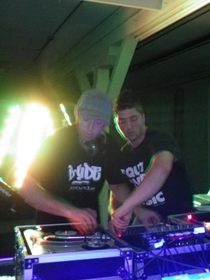 One DJ scratching while the other DJ plays with effects on the mixer