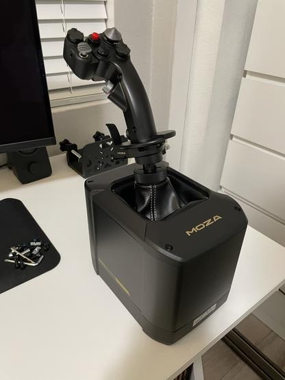MOZA MH16 grip mounted to a MOZA AB9 FFB (Force Feedback) base sitting on a white desk with a mounting bracket in the background.